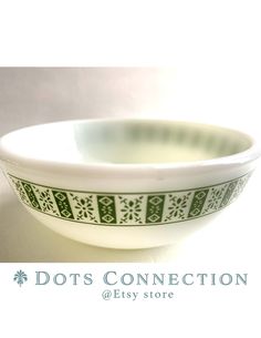 a white and green bowl sitting on top of a table next to a sign that says dots connection