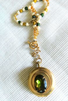 "WINTER LOCKET COLLECTION and SO MUCH LOCKET LOVE! This Vintage Gold Round Pocket Watch Two Photo Locket has a deep green crystal-faceted center stone and multi-shape assorted beaded chain also in shades of dark green, gold, mustard and cream pearls. Add a little brass leaf connector and gold toggle closure, and you're ready for daytime or evening...and perfect Valentine Gift. This one-of-a-kind solid brass piece measures 1.25 in diameter and the chain measures 16.0 inches.  It is in very good v Watch Locket, Gold Pocket Watch, Vintage Pocket Watch, Green Oval, Pearl Cream, Rich Green, Photo Locket, Bead Chain, Crystal Stone