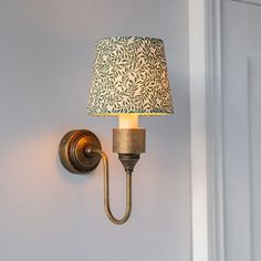 a wall light with a green and white shade on it's side next to a door