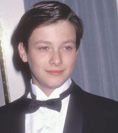 a young boy wearing a tuxedo and bow tie