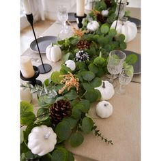 the table is set with white pumpkins and greenery