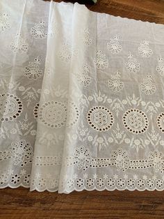 two pieces of white lace sitting on top of a wooden table