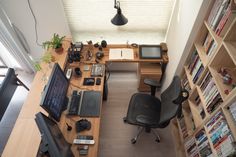 an overhead view of a home office with computer equipment and bookshelves in the background