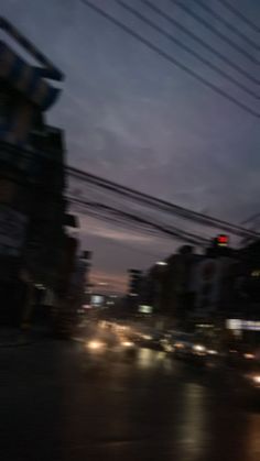 blurry image of city street at night with traffic lights and power lines in the foreground