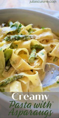 creamy pasta with asparagus and parsley in a white bowl on a wooden table