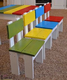 four colorful wooden chairs sitting on top of a carpeted floor next to a fireplace