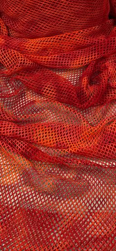 an orange and red mesh fabric is folded up on top of each other in rows