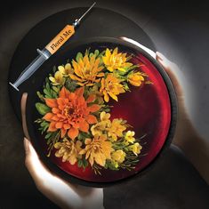 a person holding a plate with flowers on it and a needle in the middle that is attached to it