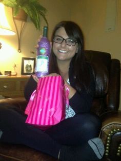 a woman sitting in a chair holding a pink bag and a purple paper shopping bag