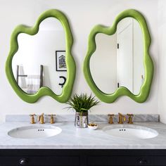 there are two mirrors on the wall above the sinks in this bathroom, one is green and the other is white