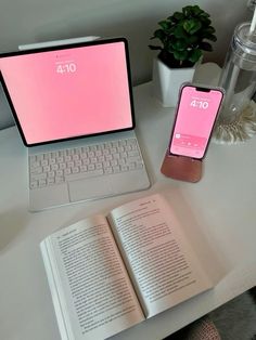 an open laptop computer sitting on top of a white desk next to a pink iphone