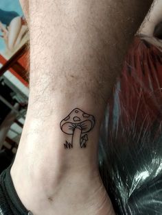 a small mushroom tattoo on the ankle is shown in black and grey ink, with an arrow at the bottom