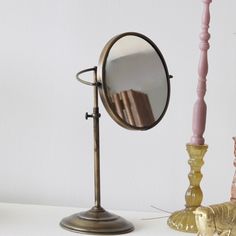 a mirror sitting on top of a table next to a candle and some candlesticks