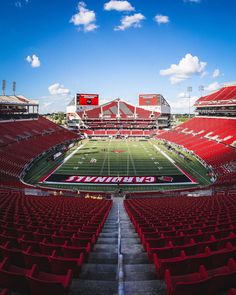 an empty stadium filled with red seats under a blue sky