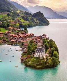 an island in the middle of water with houses on it and boats floating near by