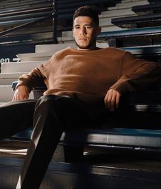 a man sitting on top of a bench next to a bleachers watching something