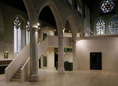 the inside of a large building with wooden floors and arches, windows, and stairs