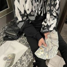 a man sitting on top of a bathroom counter holding money