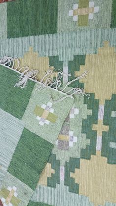 two pieces of green, yellow and white rugs on top of each other with different patterns