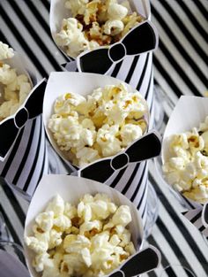 several bowls filled with popcorn sitting on top of a black and white striped table cloth