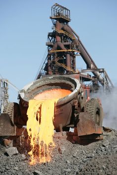 a large metal object with yellow flames coming out of it's center and on top of some rocks