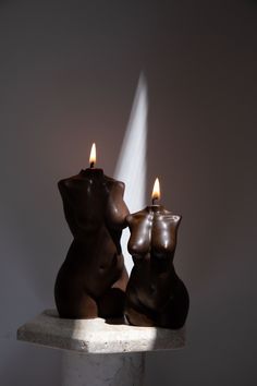 two chocolate bears sitting next to each other on top of a white pedestal with a light coming from behind them