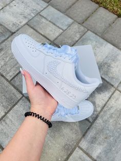 someone is holding their white nike air force sneakers