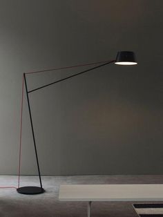 a floor lamp with a black shade on it and a white table in the background