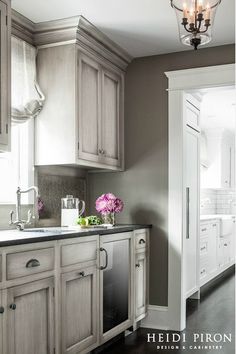 a kitchen with gray walls and white cabinets is pictured in this image, the light shines on the cabinetry