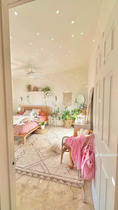 an open door leading to a bedroom with pink sheets on the bed and two chairs