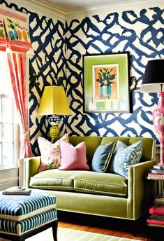 a living room with blue and white wallpaper, green couches and colorful pillows