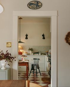 an open door leading to a kitchen with white cabinets and checkered flooring on the walls