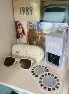 a white table topped with lots of items and sunglasses on top of it's shelf