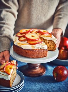 a person is holding a cake with apples on it and another slice has been cut