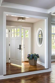 a white door with two windows and a basket full of flowers on the floor in front of it