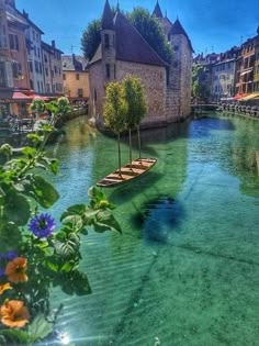 the water is crystal green and clear with flowers in front of buildings on either side