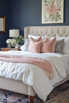 a bedroom with blue walls, white bedding and pink pillows on the headboard