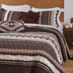 a bed with brown and white bedspread on top of it next to a night stand