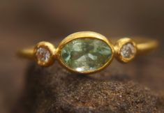 a close up view of a ring with an oval shaped green stone in the middle