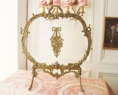 an ornate gold bed frame with pink and white pillows on top of it in a bedroom