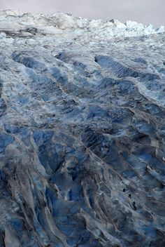 an airplane flying over the top of a glacier