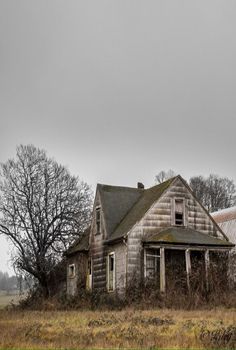 an old run down house in the middle of a field with no one around it