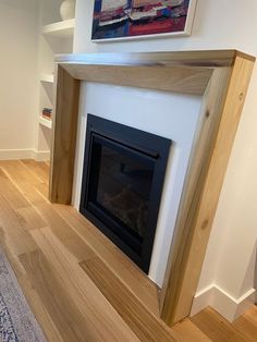 an empty room with a fire place in the center and hardwood flooring on the other side