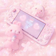 a pink teddy bear sitting next to an electronic device on a bed with bubbles all over it