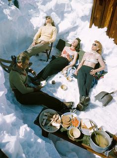 four people are sitting in the snow with food