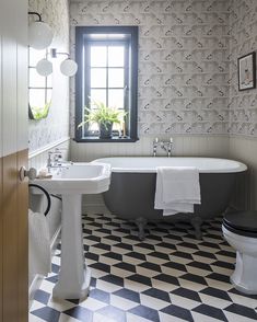 a bathroom with a black and white checkered floor, sink, toilet and bathtub