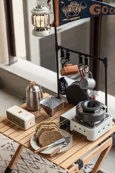 a wooden table topped with assorted items on top of a rug next to a window