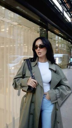 a woman standing in front of a store window with her hands on her hips and wearing sunglasses