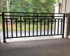 an empty balcony with black railings and wood flooring, overlooking the trees outside