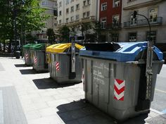 several trash cans lined up on the sidewalk